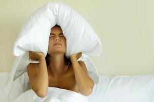mujer con almohada en la cabeza por el ruido