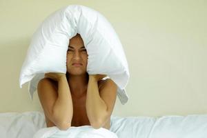 mujer con almohada en la cabeza por el ruido