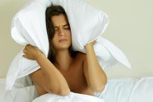 Woman with pillow on her head because of noise photo