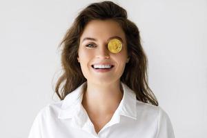 Young woman with a Bitcoin cryptocurrency on gray background photo