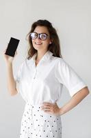 Businesswoman showing smartphone display on gray background photo