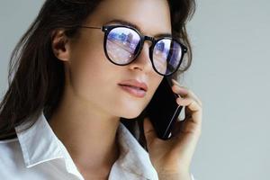 Young businesswoman in eyeglasses talking by smartphone photo