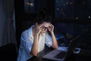 Woman is working with laptop at home during night. photo