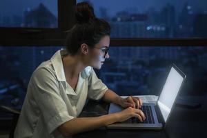 Woman is working with laptop at home during night. photo