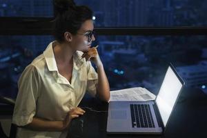 Woman is working with laptop at home during night. photo