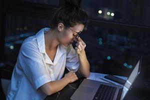 Woman is working with laptop at home during night. photo