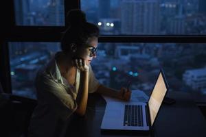 la mujer está trabajando con una computadora portátil en casa durante la noche. foto