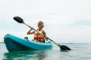 Happy young woman kayaking on the lake photo