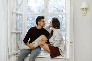 pareja sentada en el alféizar de la ventana en un día frío y nevado foto