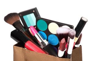 Different makeup objects in shopping bag on white photo