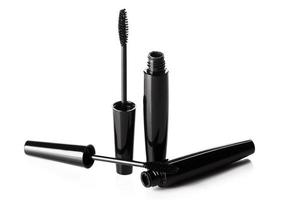 Black mascara brushes and containers on white background photo