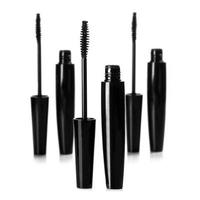 Black mascara brushes and containers on white background photo
