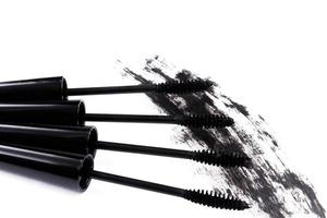 Brushes wands and smudged mascara on white background photo