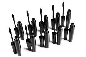 Black mascara brushes and containers on white background photo