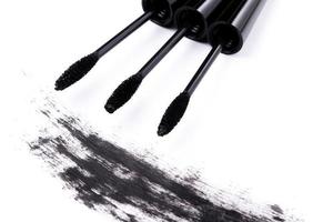 Brushes wands and smudged mascara on white background photo