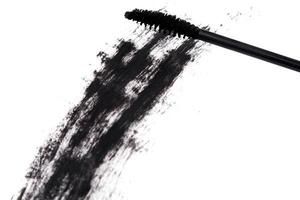 Black wand and smudged mascara on white background photo