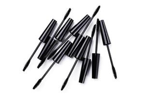 Black mascara brushes and containers on white background photo