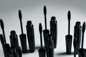 Black mascara brushes and containers on gray background photo