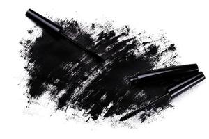 Black wand and smudged mascara on white background photo