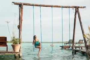 Beautiful woman on the swings which above a water photo