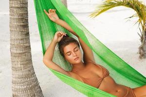 Happy and beautiful woman lying in the hammock photo