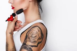 Young woman tattooist with a tattoo-machine in her hand photo