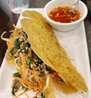 Vietnamese cuisine. Banh Xeo crepes stuffed with pork, shrimp, onions and bean sprouts and a spicy sauce closeup on a plate on the table. photo