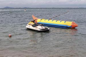 jet ski y un bote banana amarillo para atracción familiar en la playa. foto