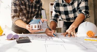 Scale model house on table with architects. Two architects making architectural model in office together. to form a new buildin photo