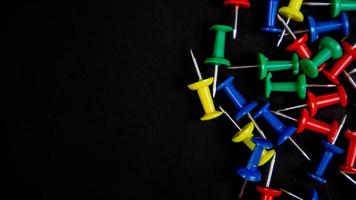 multicolored thumbtacks on a black background photo