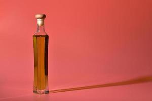 Edible oil in glass bottle isolated on pink background photo