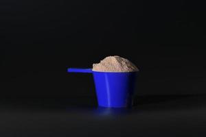 Whey protein in blue measuring scoop. Food supplement photo