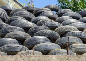 Wall of old tires. Unusual decoration of the land. Wheel fence.  Penetration protection photo