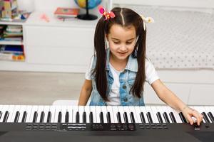 niña tocando el piano en la sala de estar en casa foto