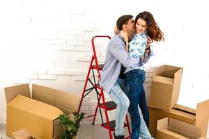 Smiling couple leaning on boxes in new home photo