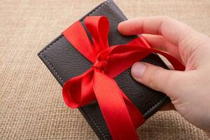 Hand holding a wallet wrapped with ribbon photo