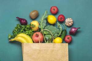 bolsa de papel ecológica con vegetales verdes orgánicos crudos aislados en fondo verde plano, vista superior cero desperdicio, concepto libre de plástico dieta saludable y desintoxicación, concepto de agricultura foto