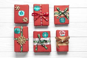 Handmade wrapped red, green gift boxes decorated with ribbons, snowflakes and numbers, Christmas decorations and decor on white table Xmas advent calendar concept Top view Flat lay Holiday card photo