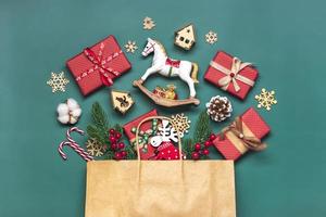 cajas de regalo rojas envueltas a mano decoradas con cintas, copos de nieve y números, adornos navideños y decoración en bolsa sobre mesa verde concepto de calendario de adviento de navidad vista superior tarjeta de vacaciones plana foto