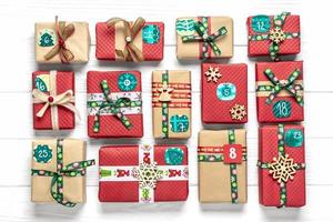 Handmade wrapped red, green gift boxes decorated with ribbons, snowflakes and numbers, Christmas decorations and decor on white table Xmas advent calendar concept Top view Flat lay Holiday card photo