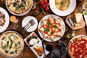 variedad de comida italiana en la mesa, pizza, pasta y aperitivos foto