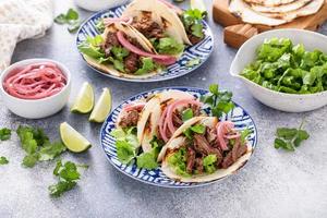 Beef tacos with lettuce and pickled red onion photo