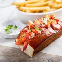 rollo de langosta con papas fritas en un tablero de mármol foto