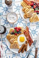 mesa de desayuno con gofres. huevo frito, bacon y salchicha foto