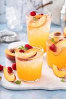 Refreshing summer cocktail with peach and raspberry photo