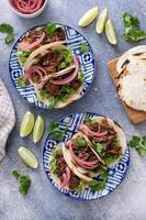 Beef tacos with lettuce and pickled red onion photo