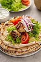 Chicken souvlaki with fresh vegetables on a flatbread photo