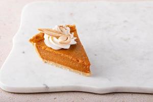 Pumpkin pie slice topped with whipped cream photo