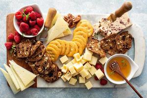 Cheese and snacks board with raspberry and crackers photo