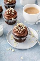 Dark chocolate cupcakes with whipped ganache frosting and white chocolate curls photo